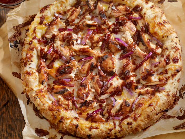 BBQ chicken pizza with sliced chicken and red onion